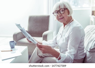 Local News. Pleasant Stylish Elegant Elderly Lady Feeling Joyful While Reading Local News At Home