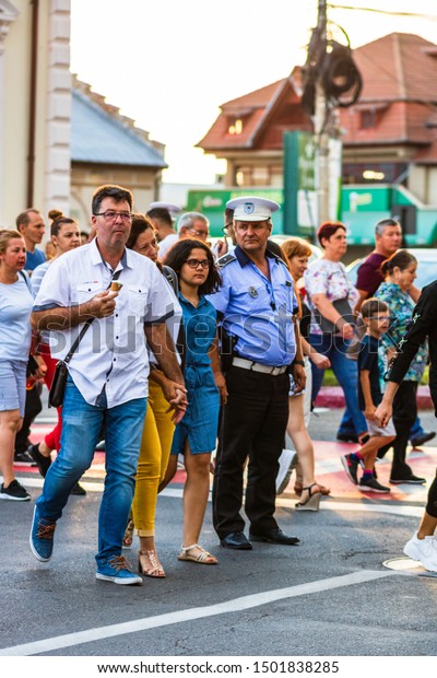 Local police man on duty\
directing traffic on a national holiday in Targoviste, Romania,\
2020
