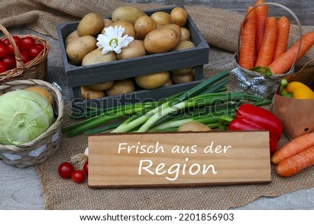 Local vegetables with the text frisch aus der Region on a wooden sign, frisch aus der Region means fresh from the region.