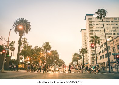 Locals and tourists walking on zebra crossing on Ocean Ave in Santa Monica after sunset - Crowded streets of Los Angeles and California state - Warm desat twilight color tones with blurred people