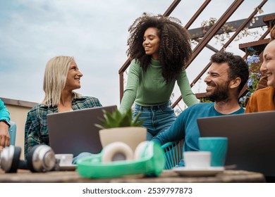 Location independent professionals sharing coworking space at cafe terrace. Contemporary nomadic lifestyle with diverse group working remotely in natural garden environment - Powered by Shutterstock