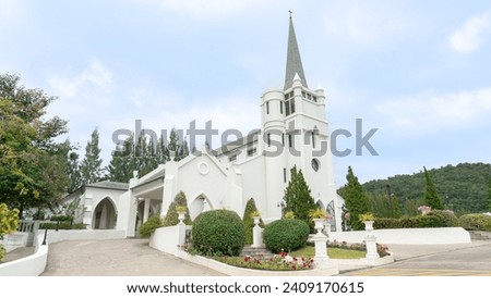 Location photos Tall European Church The pitched roof has a cross that sends devotion to God in heaven. The building is white and clean, like a land of paradise. Colorful flower bushes decorate the fr