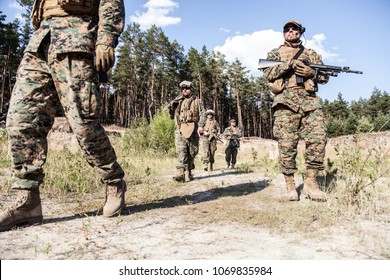 Location shot of United States Marine with rifle weapons in uniforms. Military equipment, army helmet, warpaint, smoked dirty face, tactical gloves. Military action, battlefield