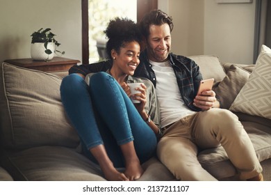 Lock The Door, Leave The World Outside. Shot Of A Happy Young Couple Using A Digital Tablet While Relaxing On A Couch In Their Living Room At Home.