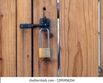 Lock Hanging From A Latch On A Redwood Fence.