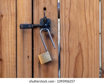 Lock Hanging From A Latch On A Redwood Fence.