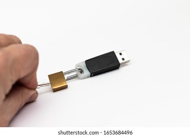 A lock on a flash drive is opened by a hand with a key. Close-up. The concept of cyberthreats and information storage security.