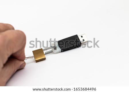 A lock on a flash drive is opened by a hand with a key. Close-up. The concept of cyberthreats and information storage security.