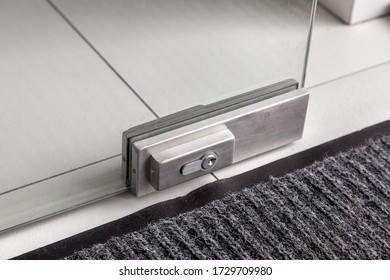 The Lock On The Glass Door, The Metal Mechanism Of Locking The Doors With The Keyhole On The Glass Office Door On The Floor With Foot Mat, Close Up Detils.