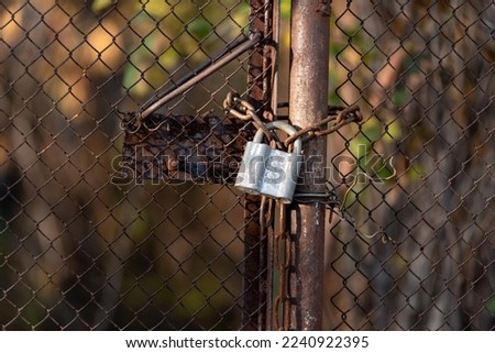 lock on an old rusty mesh gate, chain link fence