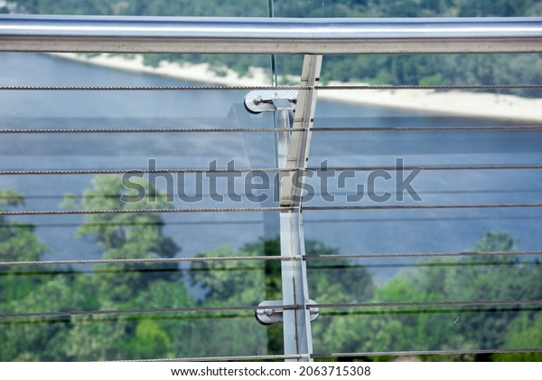 lock\
sling steel and screw of detail of clamps system on glass bridge\
with tensioners engineering construction stainless steel turnbuckle\
on background river with shore and treees,\
nobody.