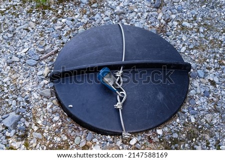 A lock and steel cable secures the lid of an underground tank