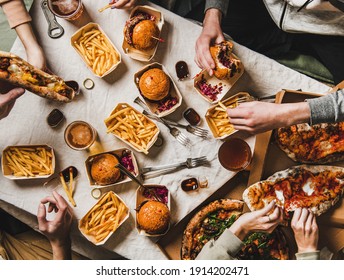 Fastfood-Dinner bei der Familie bei der Abholung. Gruppe von Freunden im Flachbildschirm, die Burger, Pommes frites, Sandwiches, Pizza, Bier zu Hause auf Tischhintergrund trinken, Draufsicht