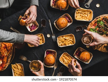 Lockdown Family Fast Food Dinner From Delivery Service. Flat-lay Of Friends Having Quarantine Home Party With Delivered Burgers, Fries, Sandwiches, Pizza, Beer Over Dark Table Background, Top View