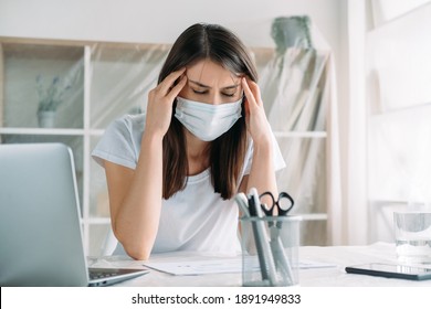 Lockdown Furlough. Office Move. Quarantine Unemployment. Stressed Out Anxious Female Employee In Protective Face Mask Suffering From Headache At Light Workplace With Covered Furniture.