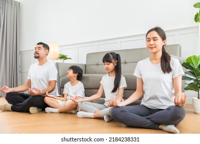 Lockdown  Good For Physical And Mental Health. Calm Parents And Children Doing Yoga At Home. Happy Asian Family With Kids Sitting And Practicing Meditation.