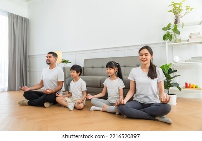 Lockdown  Good For Physical And Mental Health. Calm Parents And Children Doing Yoga At Home. Happy Asian Family With Kids Sitting And Practicing Meditation.