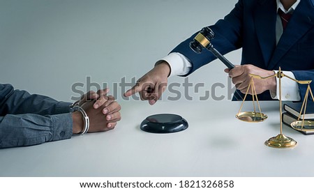 Locked Man Hands and scales of justice with a lawyer holding a hammer pointing to the hand 