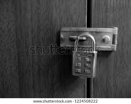 Locked padlock and iron hasp at wooden door. Black and white. Creative concept.