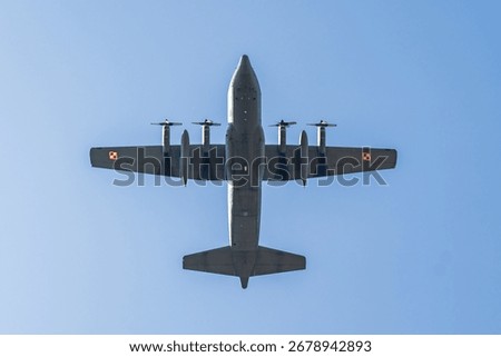 Lockheed C-130 Hercules flying over a clear blue sky during a sunny day in a serene location