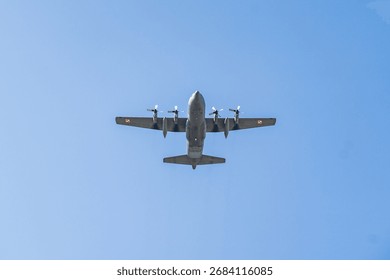 Lockheed C-130 Hercules soaring high in clear blue skies during a training mission over a coastal area