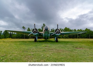 A Lockheed Hudson Bomber rests in an open field under a gloomy sky at the North Atlantic Aviation Museum in Gander, Newfoundland.