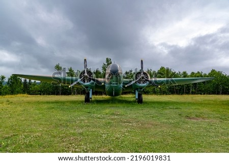 A Lockheed Hudson Bomber rests in an open field under a gloomy sky at the North Atlantic Aviation Museum in Gander, Newfoundland.