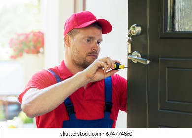 locksmith in red uniform installing new house door lock