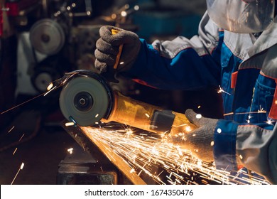 Locksmith in special clothes and goggles works in production. Metal processing with angle grinder. Sparks in metalworking. - Powered by Shutterstock