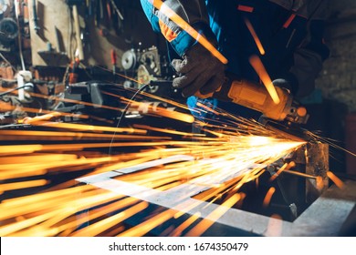 Locksmith in special clothes and goggles works in production. Metal processing with angle grinder. Sparks in metalworking. - Powered by Shutterstock