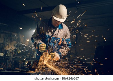 Locksmith in special clothes and goggles works in production. Metal processing with angle grinder. Sparks in metalworking. - Powered by Shutterstock