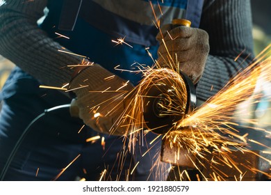 Locksmith in special clothes and goggles works in production. Metal processing with angle grinder. Sparks in metalworking. - Powered by Shutterstock