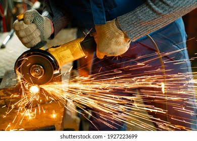 Locksmith in special clothes and goggles works in production. Metal processing with angle grinder. Sparks in metalworking. - Powered by Shutterstock