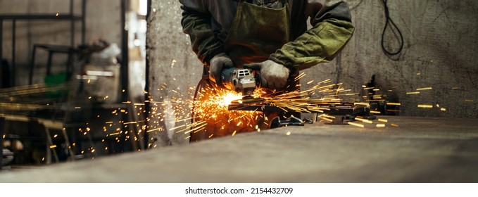 Locksmith in special clothes and goggles works in production. Metal processing with angle grinder. Sparks in metalworking. - Powered by Shutterstock