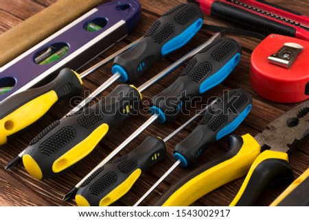 Locksmith's working tool. Mechanical assembly and disassembly tool. Screwdrivers, pliers, wire cutters, building level, tape measure, hammer, wrenches, square and other tools on a wooden surface.