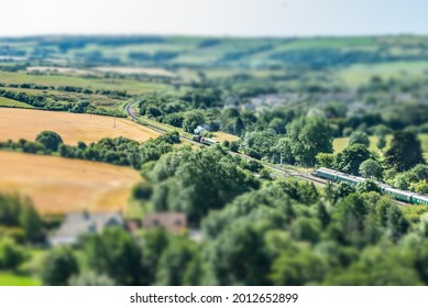 A locomotive steam train traveling along a heritage line in Dorset with tilt-shift perspective.