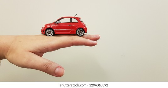 Lod, Israel - January 24 2019: Red Car Fiat 500 Metal Small Toy On Human Hand Back White Background 