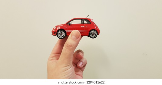 Lod, Israel - January 24 2019: Red Fiat 500 Metal Toy Car Holding In Two Fingers On White Background