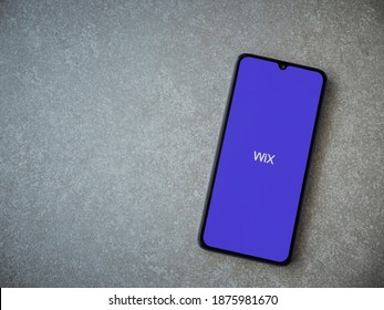 Lod, Israel - July 8, 2020: Wix app launch screen with logo on the display of a black mobile smartphone on ceramic stone background. Top view flat lay with copy space.