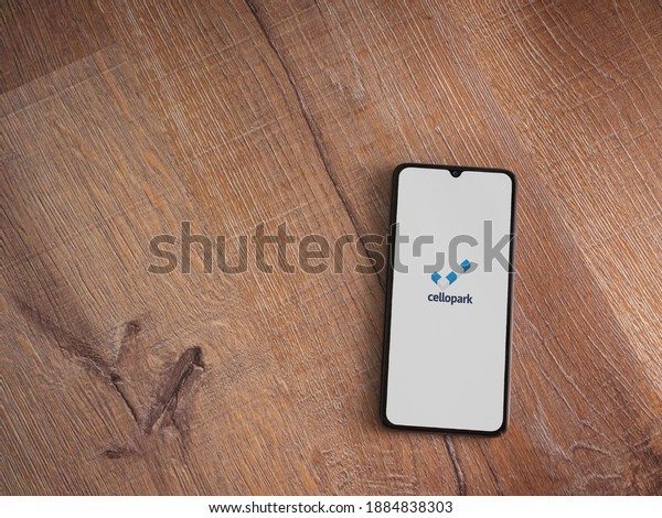 Lod, Israel - July 8, 2020:\
Cellopark app launch screen with logo on the display of a black\
mobile smartphone on wooden background. Top view flat lay with copy\
space.