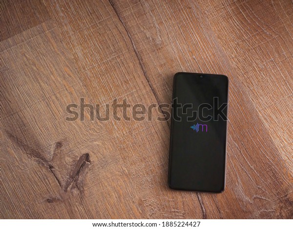 Lod, Israel - July 8, 2020:\
Miri app launch screen with logo on the display of a black mobile\
smartphone on wooden background. Top view flat lay with copy\
space.
