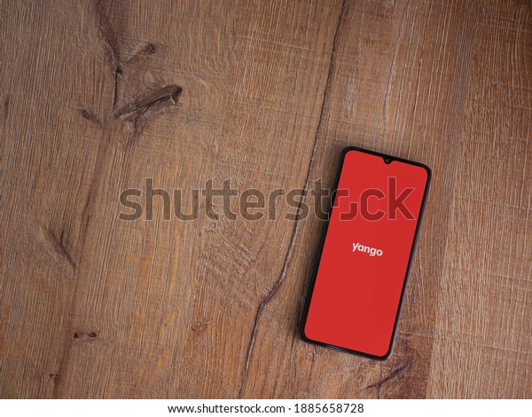 Lod, Israel - July 8,\
2020: Yango Ride app launch screen with logo on the display of a\
black mobile smartphone on wooden background. Top view flat lay\
with copy space.