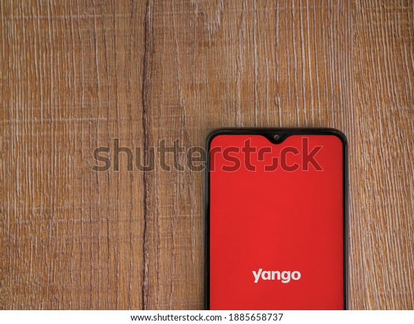 Lod, Israel - July 8,\
2020: Yango Ride app launch screen with logo on the display of a\
black mobile smartphone on wooden background. Top view flat lay\
with copy space.