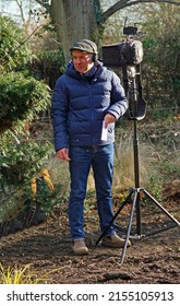 LODE, CAMBRIDGESHIRE, ENGLAND - FEBRUARY 11, 2022: BBC Sound recordist on location in a garden in winter.