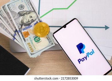 Lodz, Poland - June 21, 2022: Paypal Application On Smartphone Near Dollar Bills And Crypto Currency And And Growing Graph