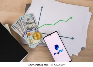 Lodz, Poland - June 21, 2022: Paypal Application On Smartphone Near Dollar Bills And Crypto Currency And And Growing Graph