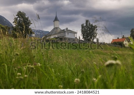The Loen Church, a parish church of the Church of Norway, pictued here from a low angle view showing the front through grass,  on an overcast evening, was built around 1330. 
