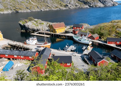 Lofoten, Norway - 20.06.2023: Traditional old fishing village on Lofoten island. Vibrant colors and old traditional buildings. Harbour area of and old fishing village. Calm fjord with old school dock