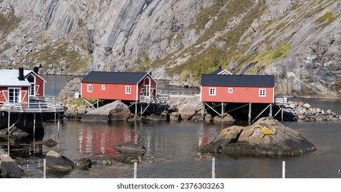 Lofoten, Norway - 20.06.2023: Traditional old fishing village on Lofoten island. Vibrant colors and old traditional buildings. Harbour area of and old fishing village. Calm fjord with old school dock