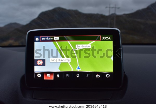 Lofoten norway  Nov 2018 Closed up gps  monitor in\
 car background with mountain ranges and electric pole in rainny\
season .It show  2dimension  route , time and speed limit at\
norway